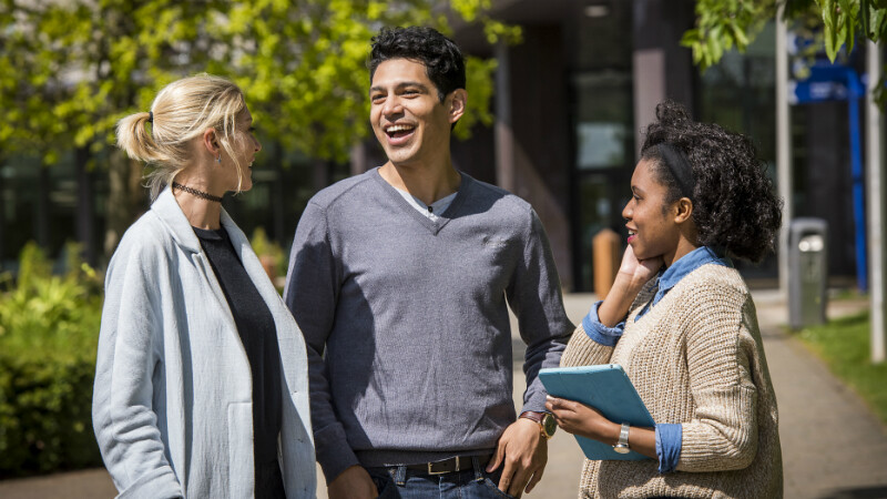 Three students smiling on campus.
