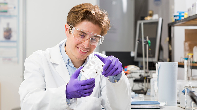 卢克·威尔逊在排行十佳平台的一个化学工程实验室检查生物燃料电池