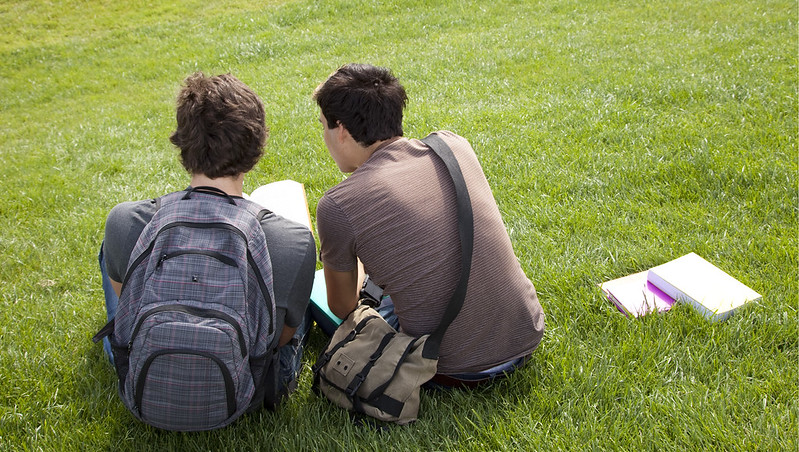 两个学生坐在草地上看书