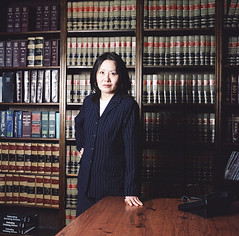 A firm-looking lawyer standing in front of a wall of books.