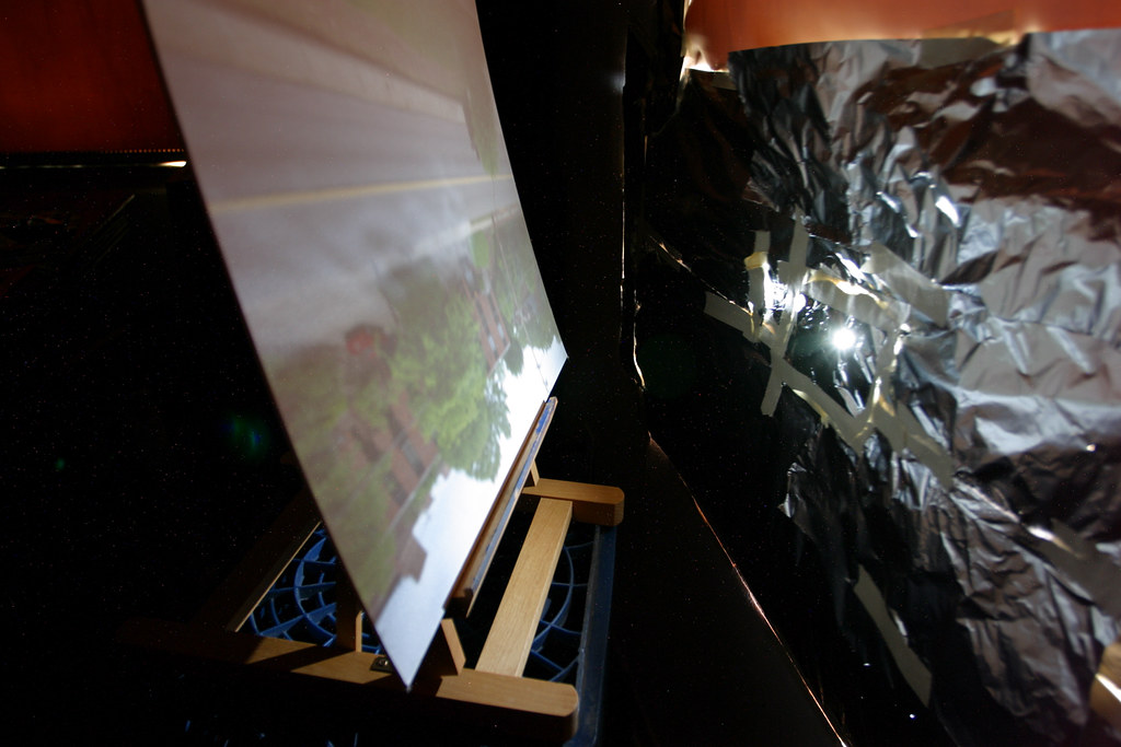 A picture of a camera obscura made in a room through a pinhole in aluminum foil