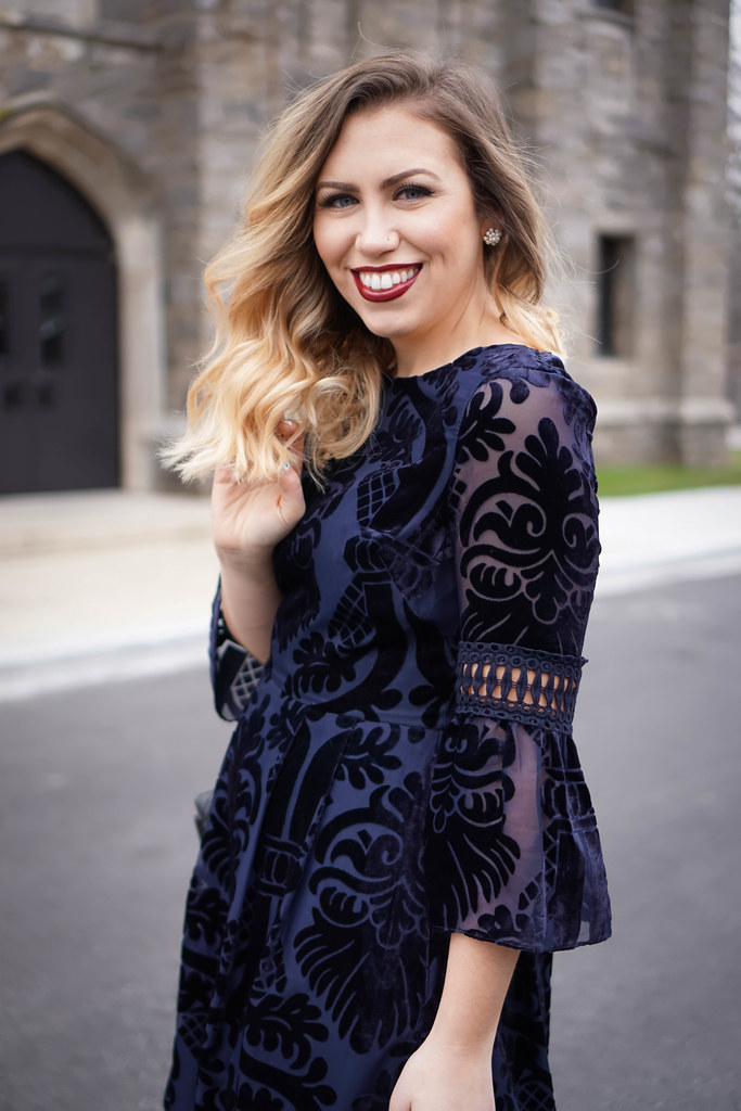 woman smiling at the camera and wearing Eliza J Embroidered Poet Sleeve Blue Velvet Dress