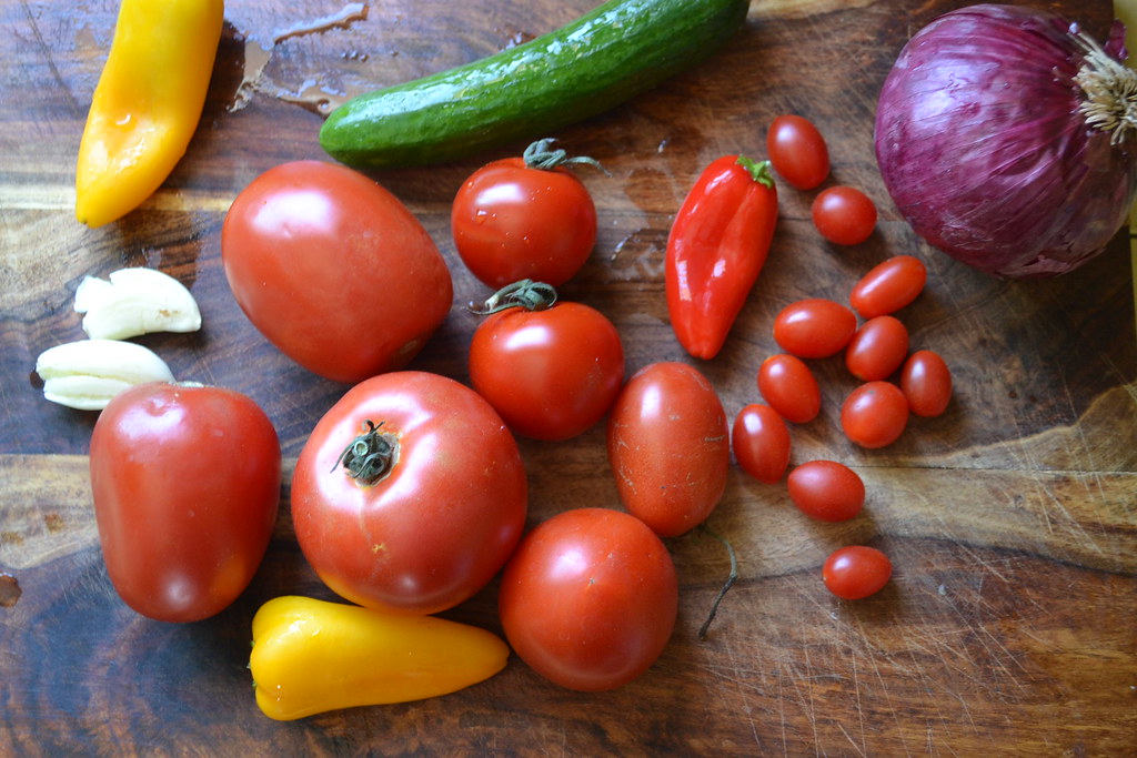 Variety of vegetables to make Spanish gazpacho, including tomatoes, bell peppers, red onion, cucumber and garlic.