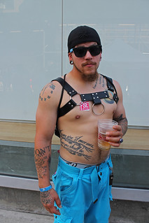 A tattoo-covered dude with a goatee and a leather harness.