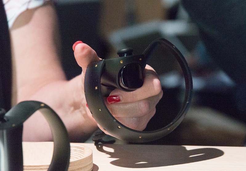 Woman holding Oculus Touch prototype (Half Moon) in left hand (rear view showing trigger button)