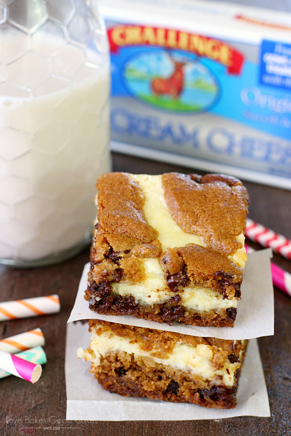 Chocolate Chip Cheesecake Bars stacked on parchment paper with a glass of milk.