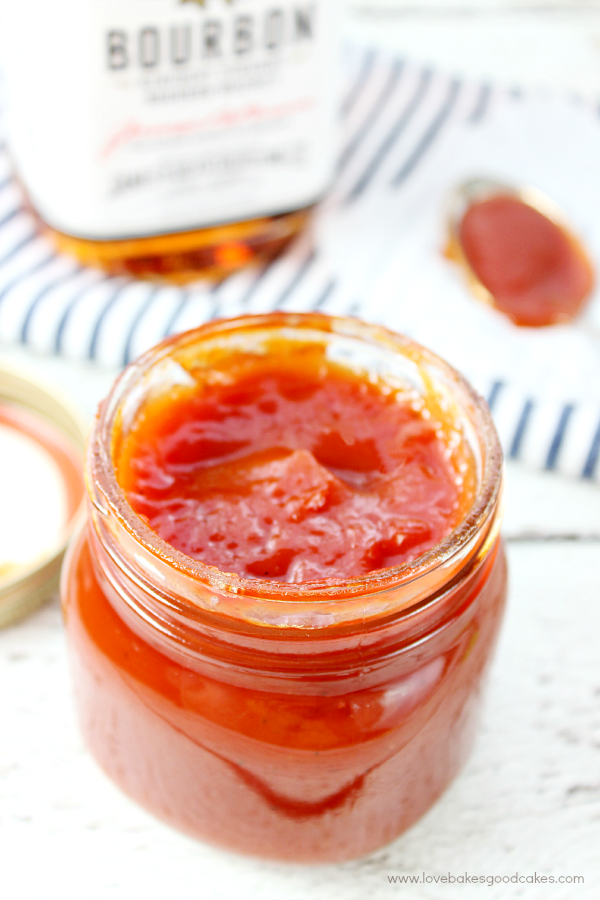 Bourbon Whiskey BBQ Sauce in a glass jar with a spoon.