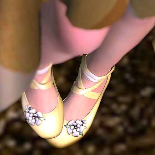 Angled downward view of a pair of ballet slippers with flowers on them.