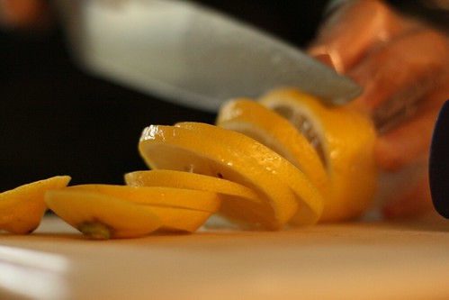 A close up of a woman's hands slicing a lemon.