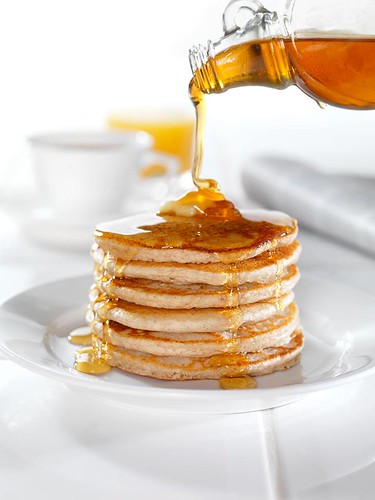 Maple syrup being poured over pancakes