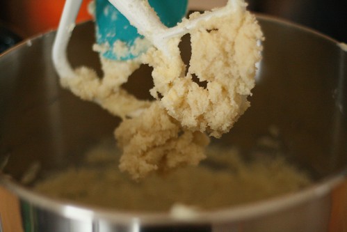 A very close-up of creamed butter and sugar stuck to the paddle attachment of a standmixer.