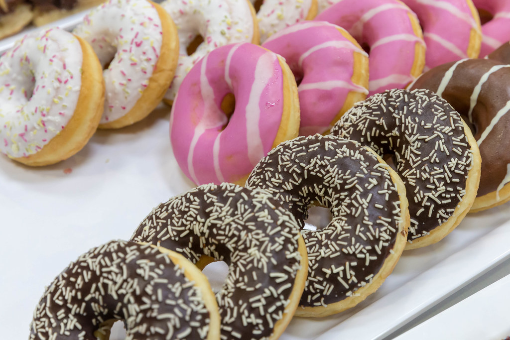 Bunte Donuts mit weißer und pinker Glasur, mit Schokoguss und bunten ...