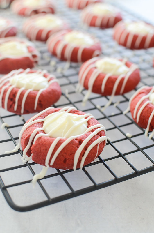 Red Velvet Peppermint Thumbprints will be Santa's new favorite cookie! Red velvet peppermint dough filled and drizzled with white chocolate!