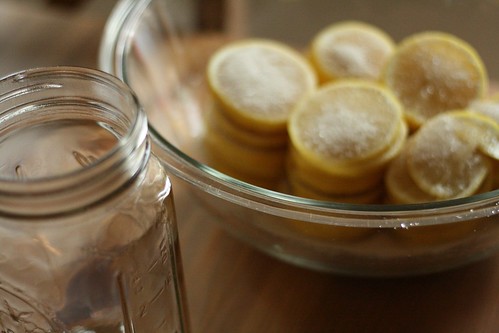 A wide-mouth quart canning jar next to a big bowl of macerating lemons.