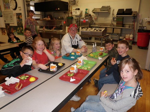 Students sitting and eating their lunch with School Chef Jason Moore
