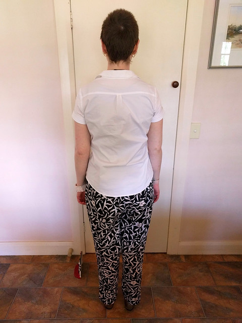 A woman wearing a short sleeve white shirt and loose, floral print pants.