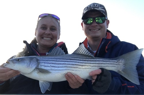 Photo of couple holding large striped bass