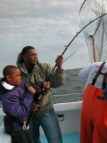 Photo of man and son reeling in a big one