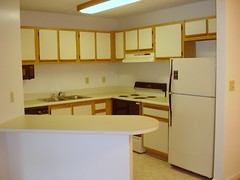 A L shaped kitchen layout with island and white cabinets.