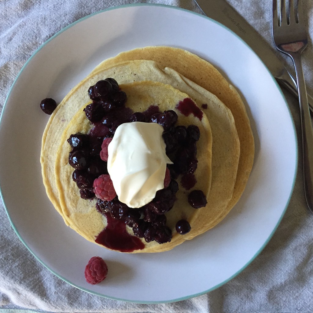 birds eye view of a stack of pancakes, topped with berry compote and a quenelle of cream