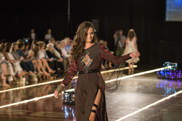 A student model walks down the runway in a two-tone dark red dress