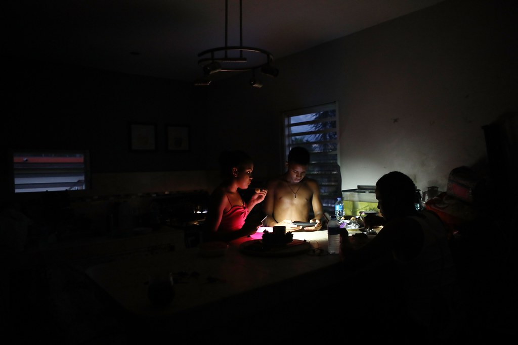 人們以手機照明，吃著晚飯。（圖片來源： Mario Tama/Getty Images）