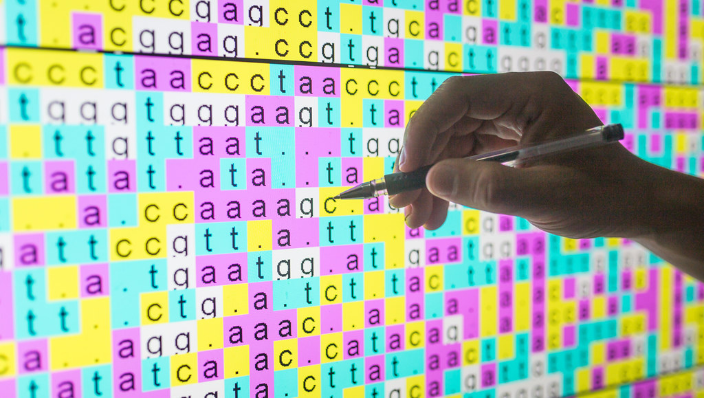 Hand pointing to DNA sequence alignment