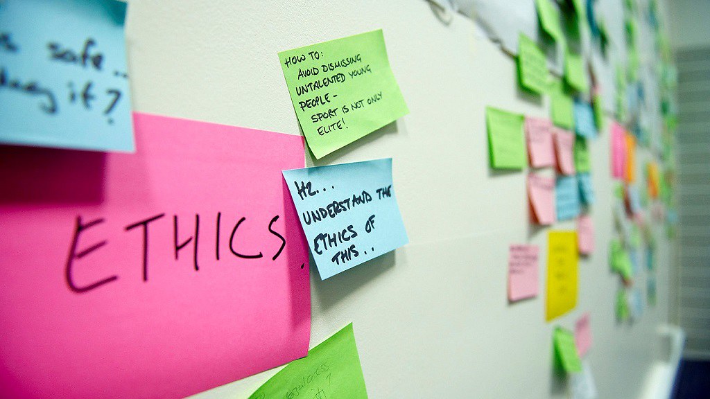 the image shows a collection of multicoloured post-it notes pinned to a wall with the word research ethics written on them. 