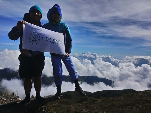The image shows Gabriel Mellejor and John Balagpo standing in the mountain with clouds in them.