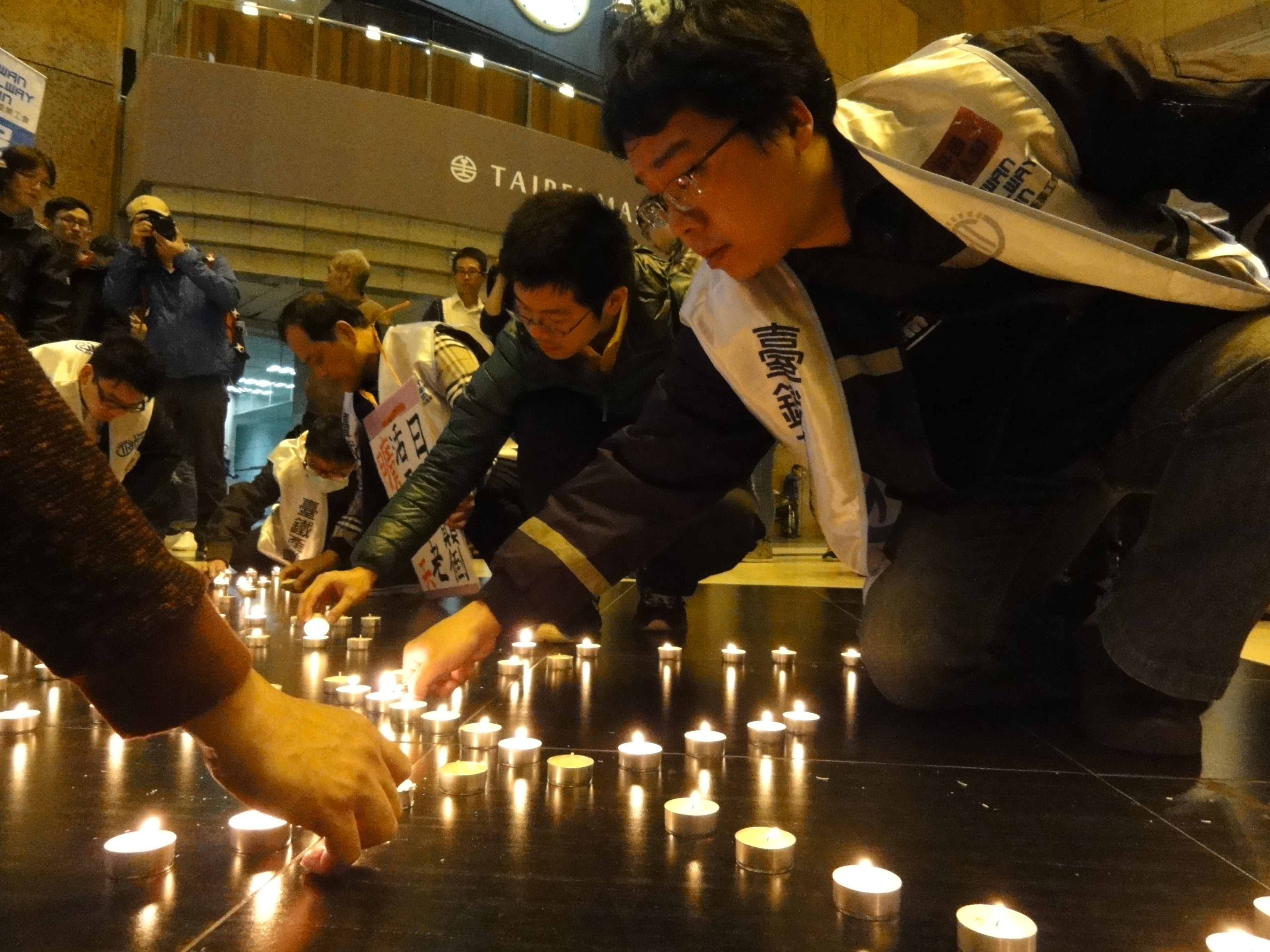 產業工會在台北車站大廳舉行晚會，將蠟燭擺成「安全」字樣，強調「唯有不過勞的勞工，才有安全的公共運輸」。（攝影：張宗坤）