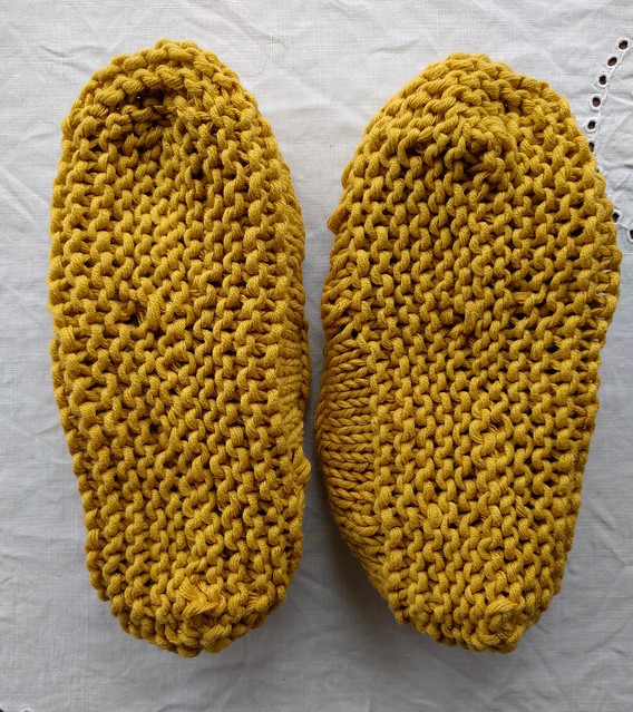 Soles of yellow handknitted mary jane slippers.