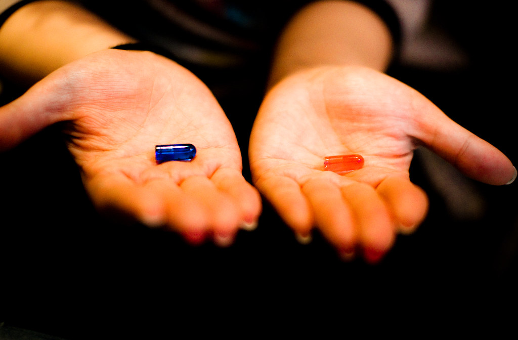 2 extended hands with 1 red pill and 1 blue pill