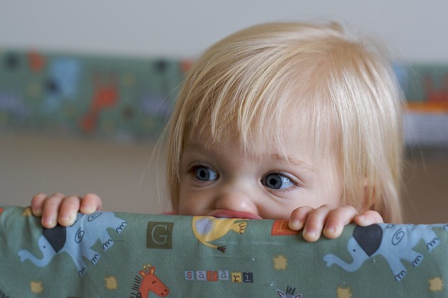 a child chews on the edge of a playpen