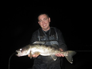 Biologist holding a walleye at night.