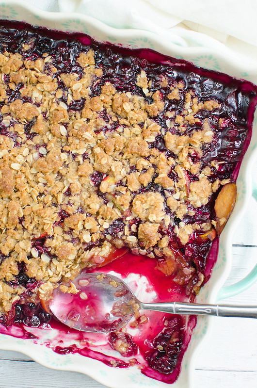 Overhead shot of peach blueberry crisp in a pan with a serving scooped out