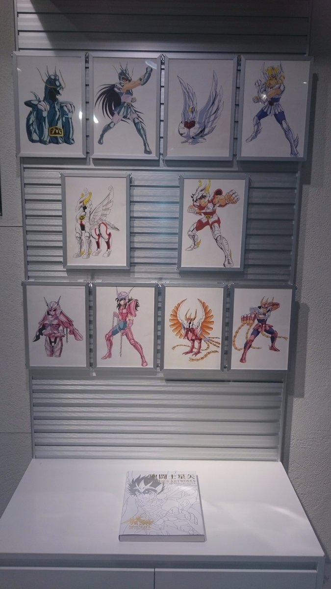 Ilustrações do anime decorando a loja. No balcão, um exemplar do artbook 