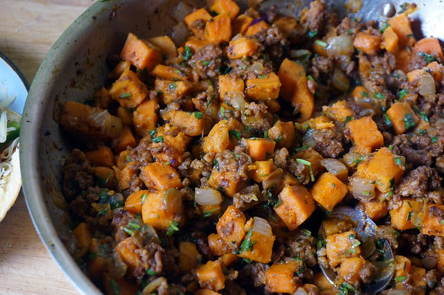 A panful of sweet potatoes and Italian sausage, soft orange cubes mixed with warm brown morsels, all flecked with cilantro. Even my sweet potato-hating father would be tempted.