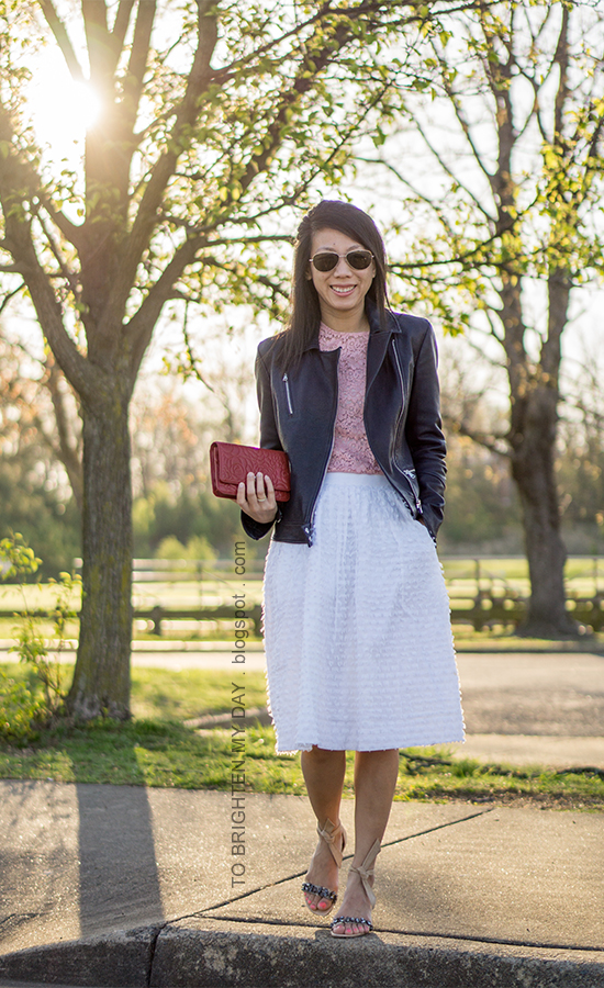 black leather jacket, pink lace top with bell sleeves, white clip dot midi skirt, stacked rings, red shoulder bag, suede sandals with jewels