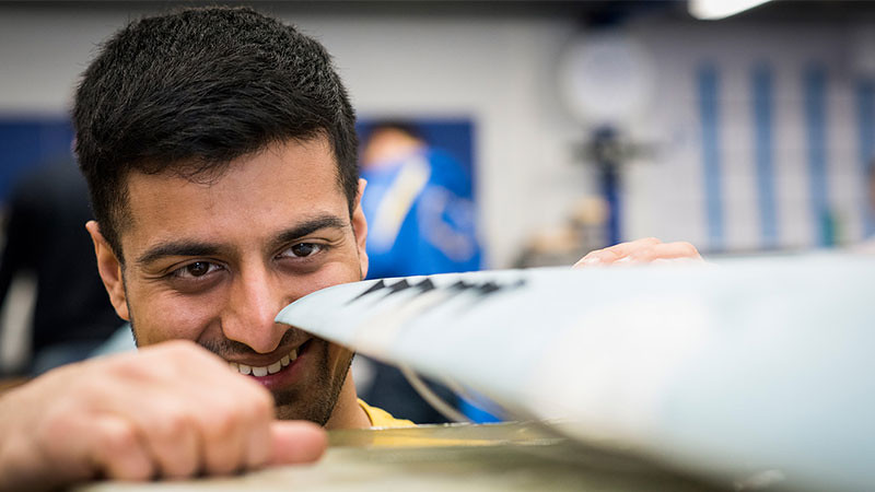 Hemant smiles as he looks at the wing of a drone.
