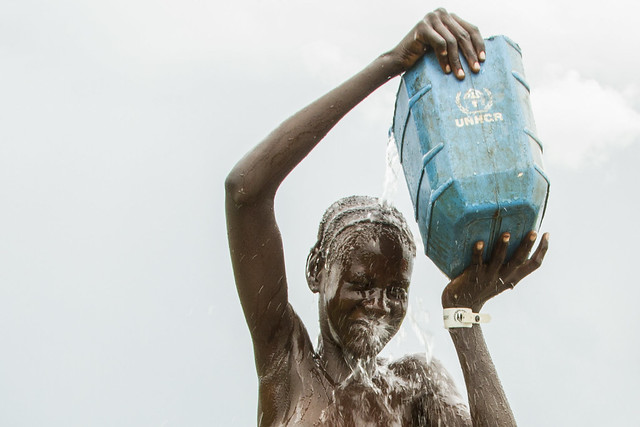 A South Sudanese refugee takes a shower with water poured from a jerry can