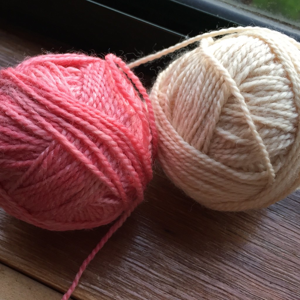 two balls of yarn, one dyed with acidified avocado pits for a subtle cream colour, one dyed with red food dye for a mid pink colour