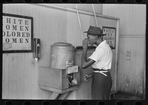 Negro drinking at "Colored" water cooler in streetcar terminal, Oklahoma City, Oklahoma (LOC)