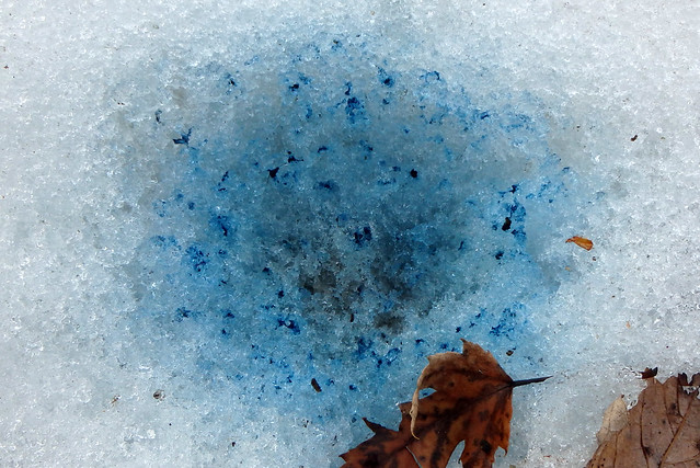 round spot of bright-blue snow, with dark blue spots, several inches wide