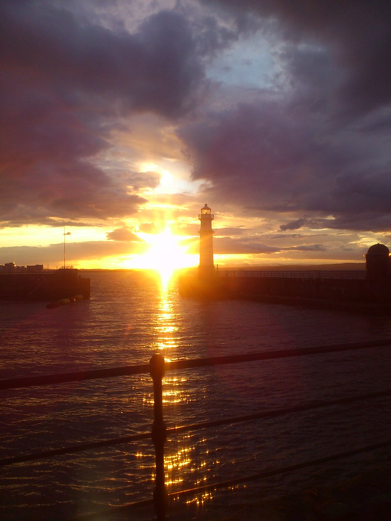 sun setting behind the lighthouse at Newhaven Harbour