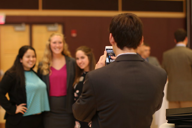 Male student taking picture of three female students with his cell phone