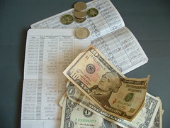 Some money sitting on top of some hand-written ledger papers.