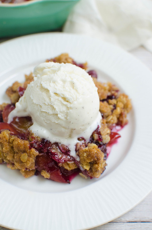 Fresh peaches and blueberries topped with a crunchy oat topping and a scoop of vanilla ice cream