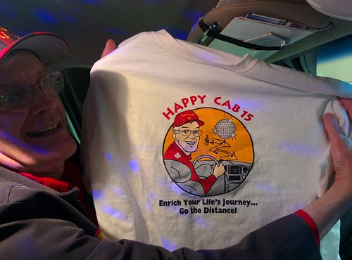 Denys holding up a T-shirt that says 'Happy Cab 15' with a cartoon version of himself and a disco ball in his cab
