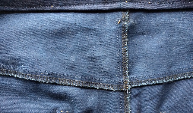 Inside a pair of jeans. The denim fabric is pilled.