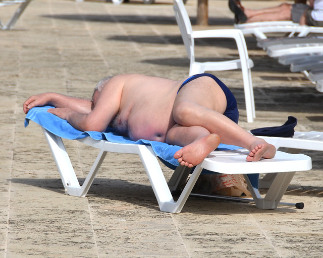Extranjero tumbado en una hamaca echando la siesta tras hincharse en el buffet del hotel